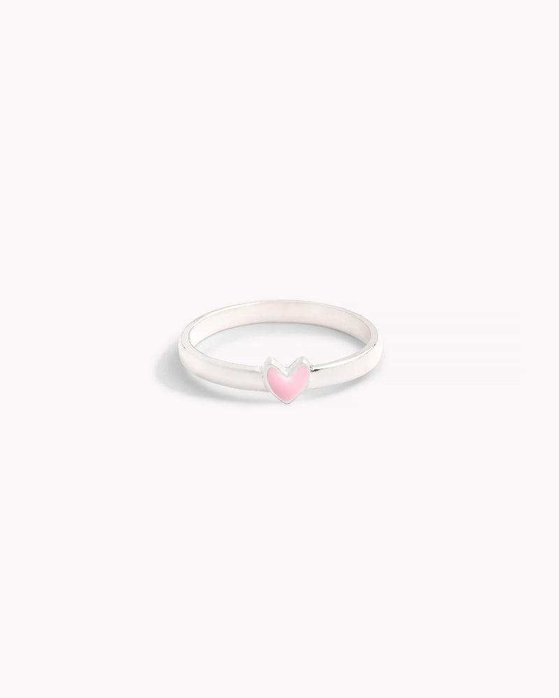 A silver ring with a classic band design and a pink heart-shaped embellishment on the top.