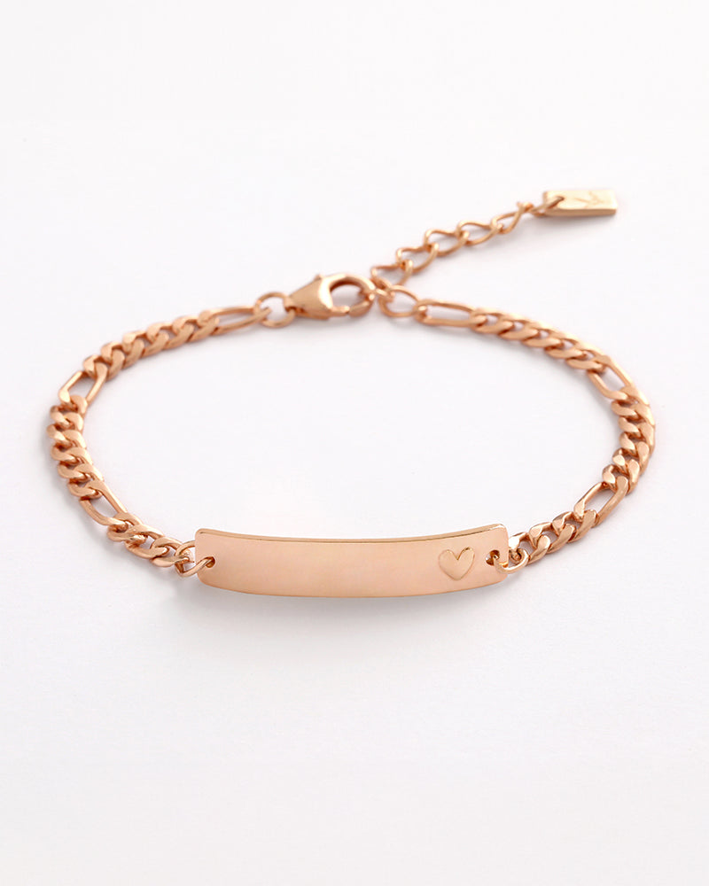 A Darling Rose Gold Bracelet featuring a solid heart detail, shown in a close-up of the engraved ID plate by Bluebird Jewellery.