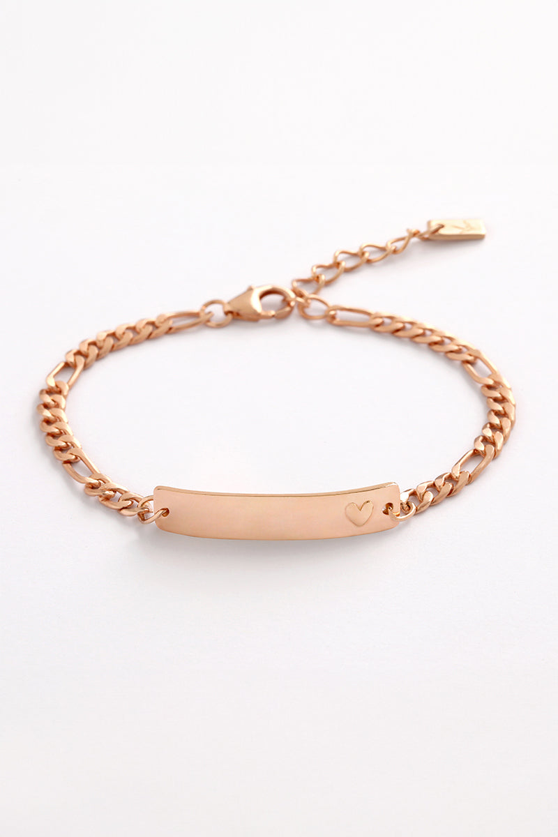 A Darling Rose Gold Bracelet featuring a solid heart detail, shown in a close-up of the engraved ID plate by Bluebird Jewellery.
