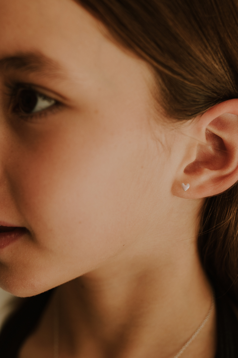 Darling Silver Earring with pink heart worn by child, close-up on ear