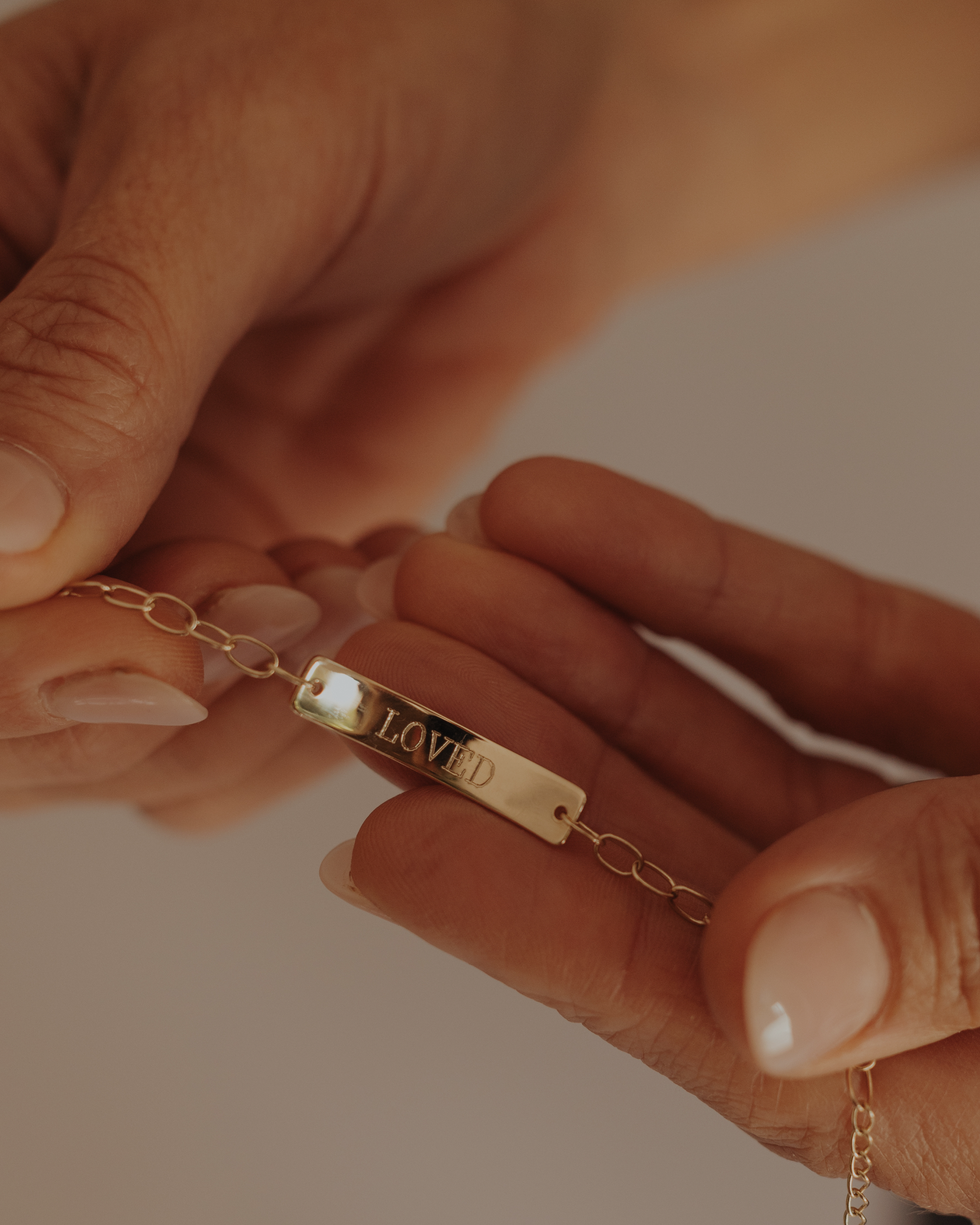 olid gold Pink Darling Bracelet engraved with "LOVED", captured in warm natural light