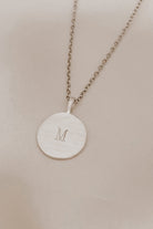 Petite signature necklace in silver with engraved M, styled for children or mums who love minimal classics.