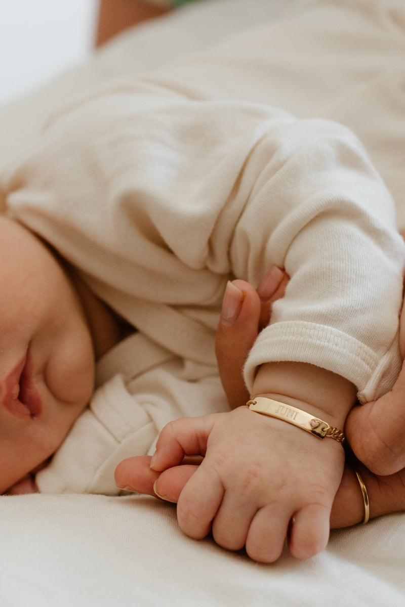 Baby wearing engraved Pink Darling Gold bracelet with heart—personalised gift for newborn milestones or keepsake moments by Bluebird Jewellery.