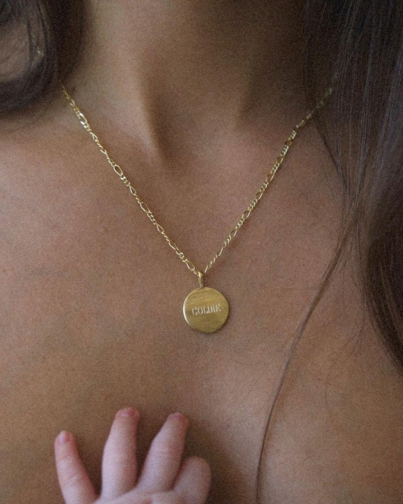 A mother is wearing the 45+5cm Signature Necklace with the name 'Goldie' engraved on the front of the pendant.