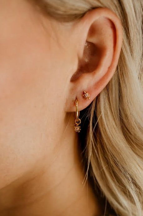 A Petite Daisy Hoop is worn alongside a Petite Daisy Stud in a woman's earlobe.  The matching Daisies complimenting one another.
