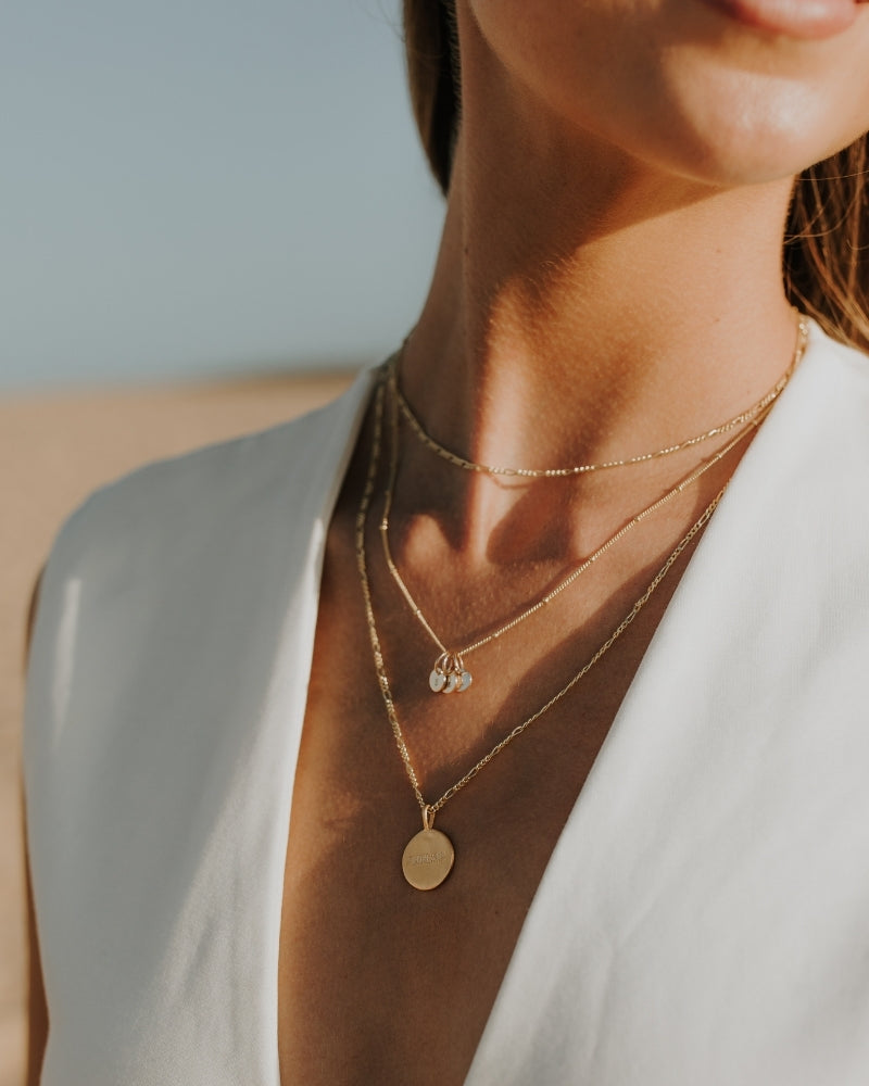 Signature Gold Necklace layered with other chains, styled at the beach for elegant, everyday wear.