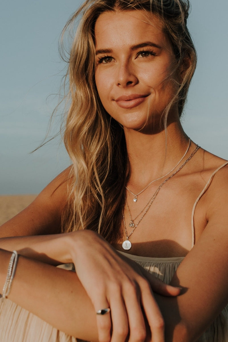 Multiple silver necklaces with engraved pendants and fine chains.