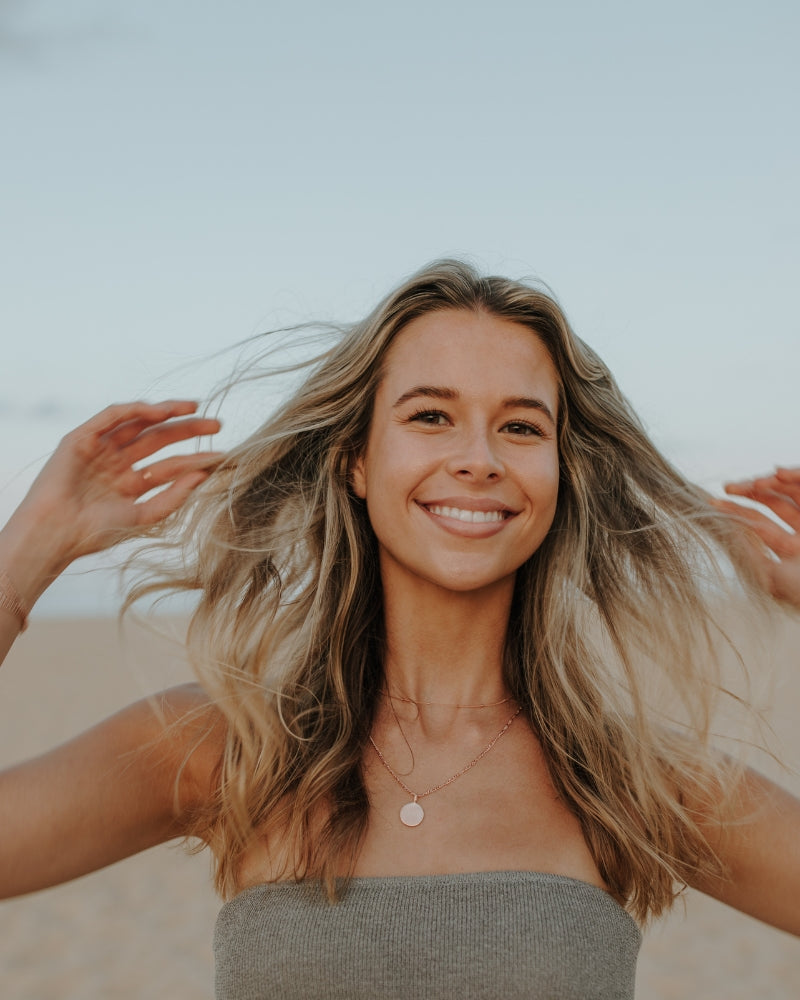 Close-up of woman smiling while wearing personalised rose gold disc necklace