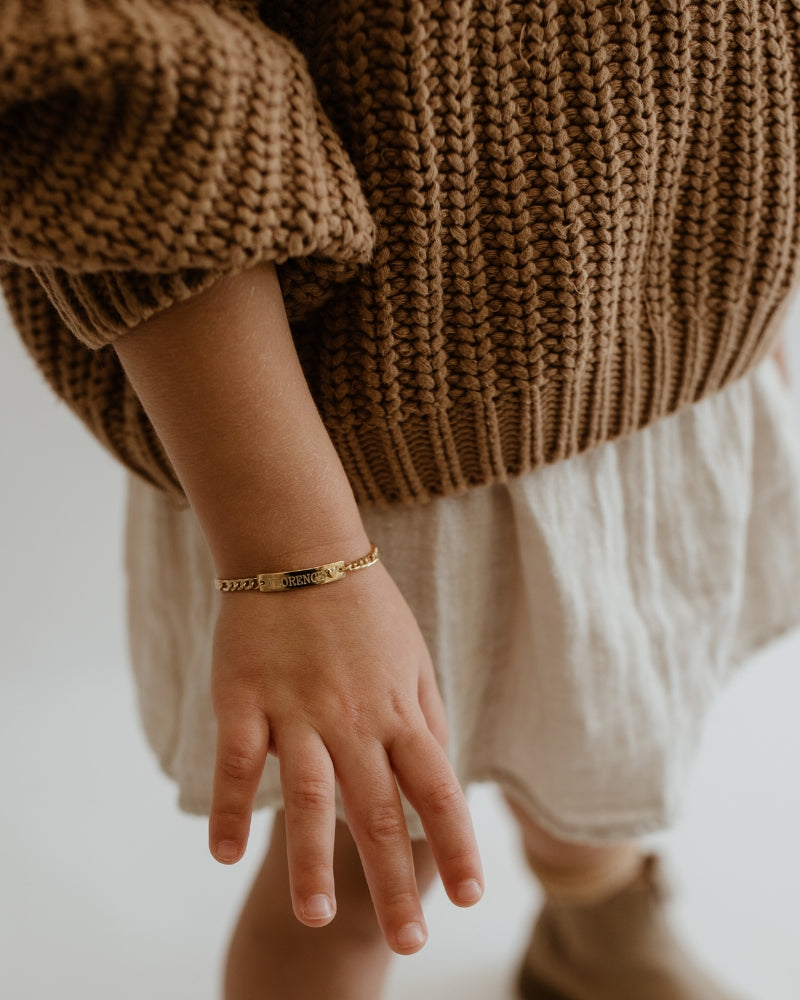 Personalised engraved gold bracelet on a child’s wrist, a keepsake jewellery piece for babies, toddlers, or growing kids by Bluebird Jewellery.