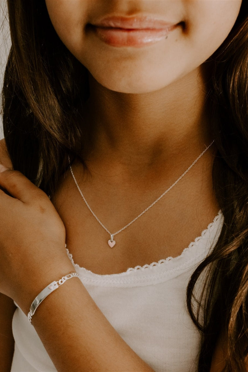 Girl wearing pink heart necklace and matching engraved silver bracelet