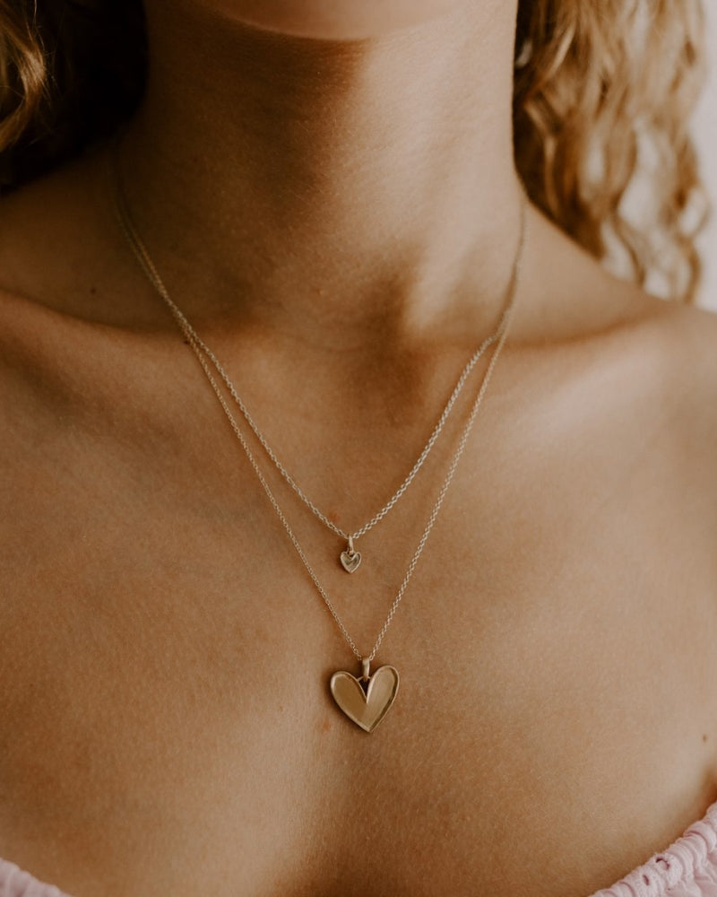 A teenage girl is wears the Petite Darling Necklace Gold layered with the Darling Necklace in Gold. The two necklaces compliment one another with a matte finish with finely raised edges and an organic surface.