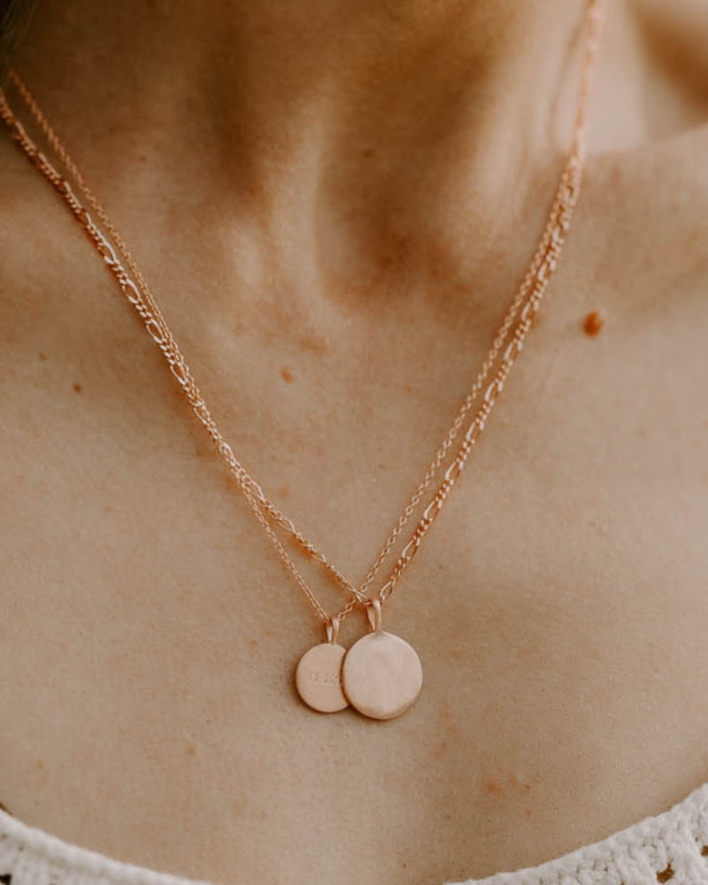 Layered Petite Signature Necklaces in rose gold with custom engravings, styled with different chain lengths on the chest.
