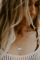 Woman wearing two engraved round silver pendants on fine chain, the Petite Signature Necklace Silver styled on neckline.