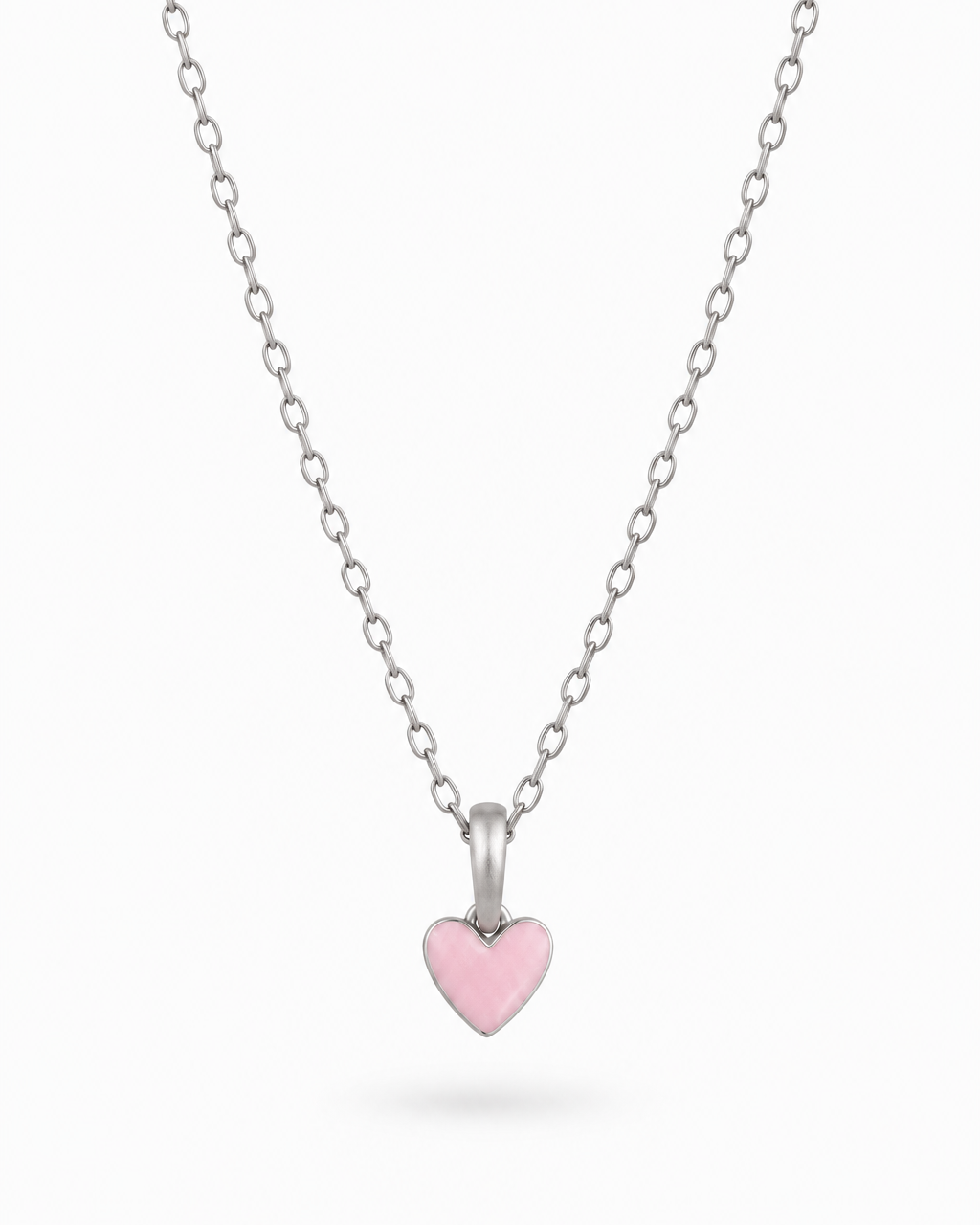 A delicate silver chain necklace featuring a small, polished silver heart pendant with a smooth, light pink enamel center, displayed against a clean white background.