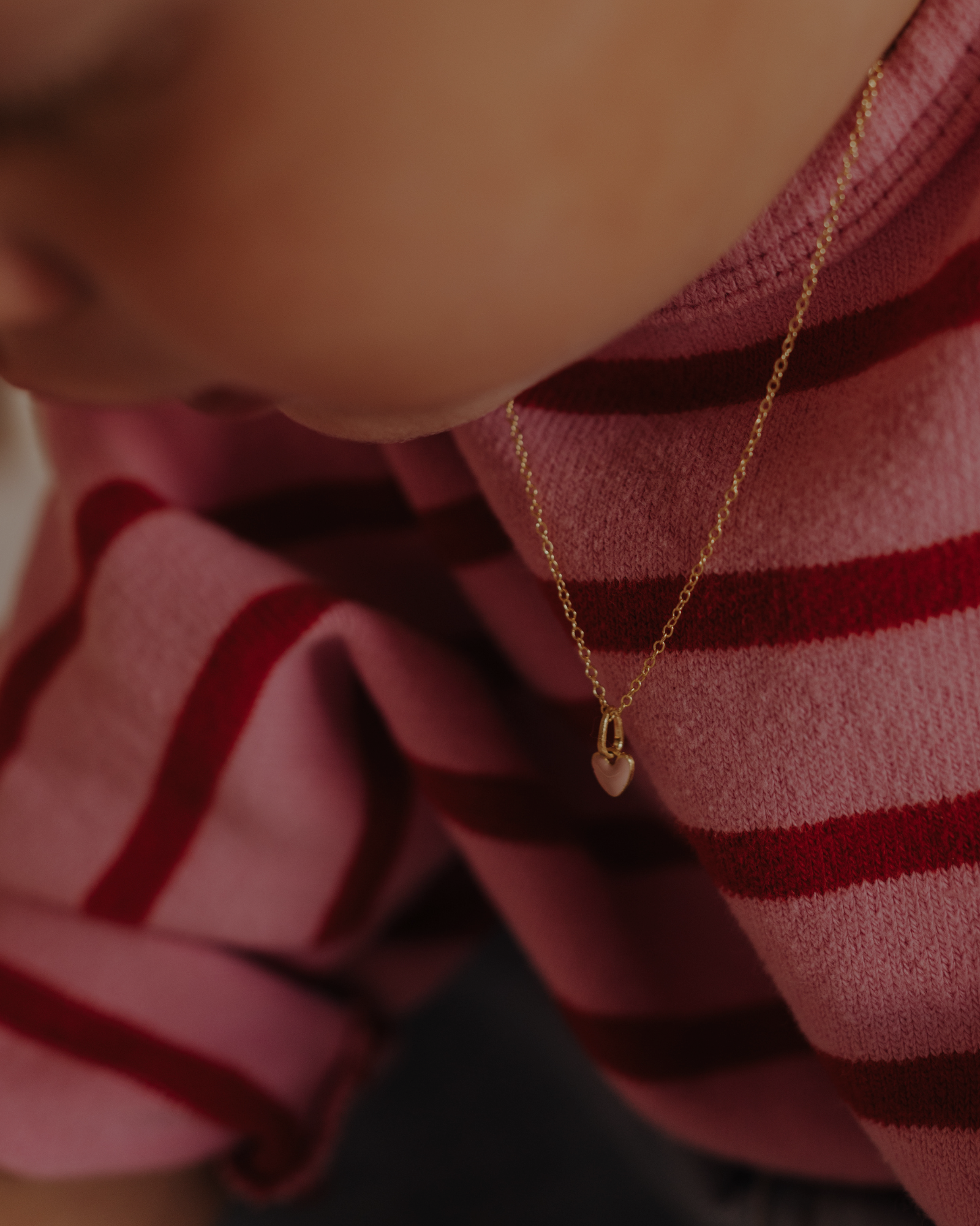 Pink Petite Darling gold necklace with enamel heart charm on child’s neck