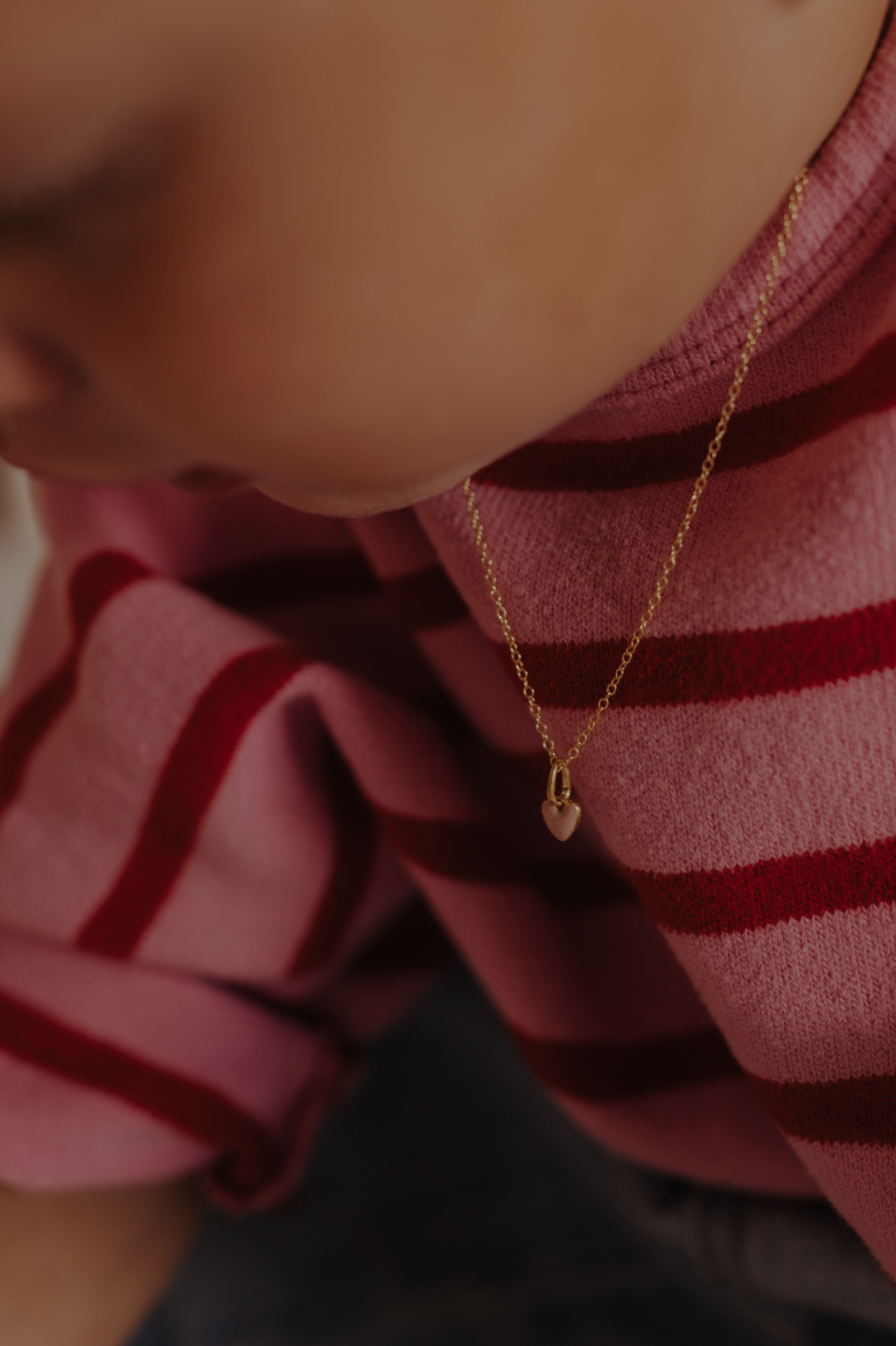 Pink Petite Darling gold necklace with enamel heart charm on child’s neck