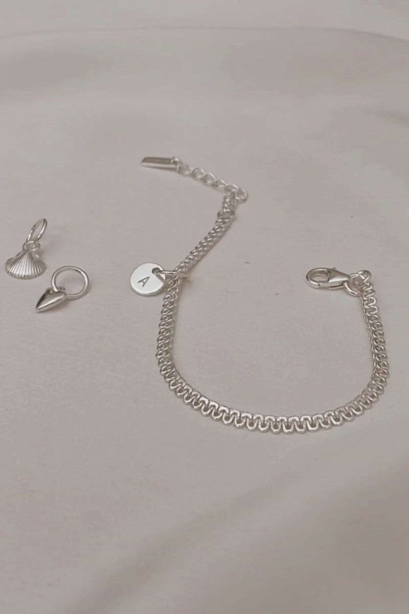A styling video showing the Lace Chain paired with engraved charms and pendants for a refined personalised jewellery look.
