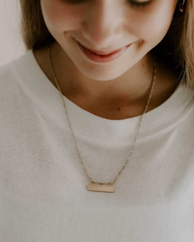 Gold signature bar necklace with engraved name, worn by a teen girl. A timeless, meaningful personalised piece.