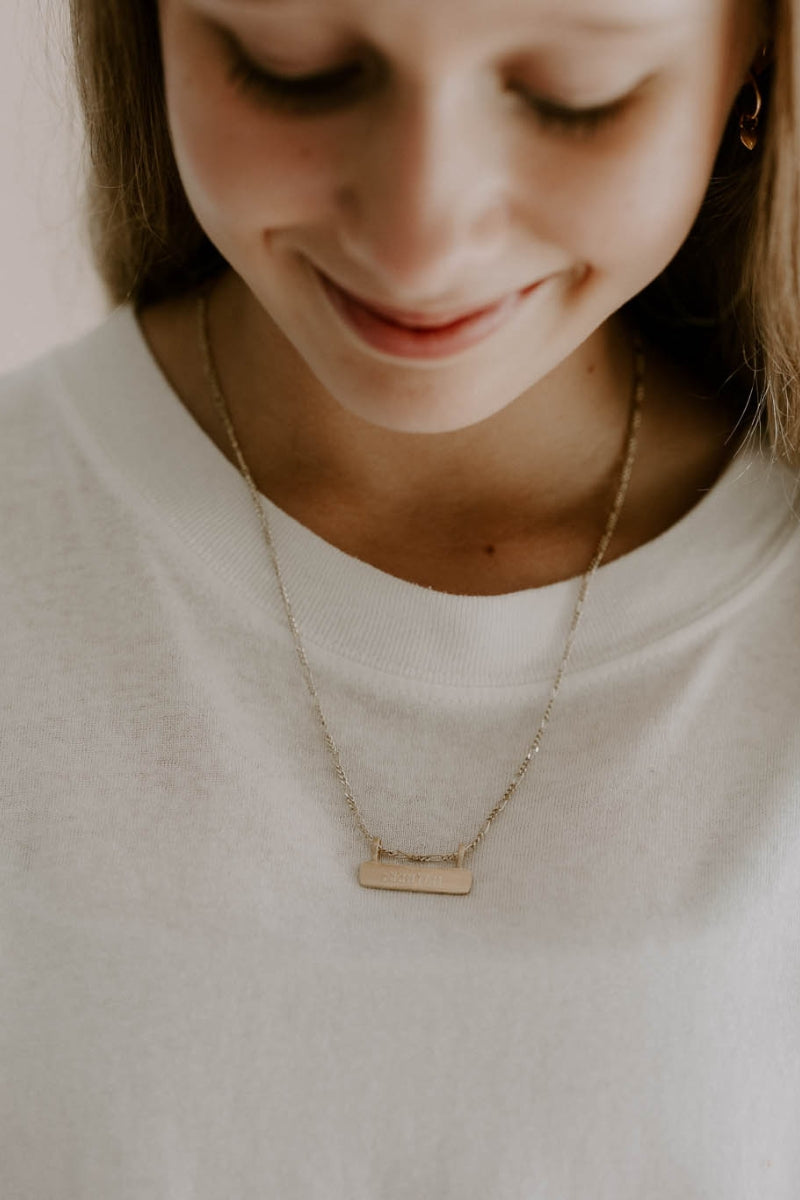 Gold signature bar necklace with engraved name, worn by a teen girl. A timeless, meaningful personalised piece.
