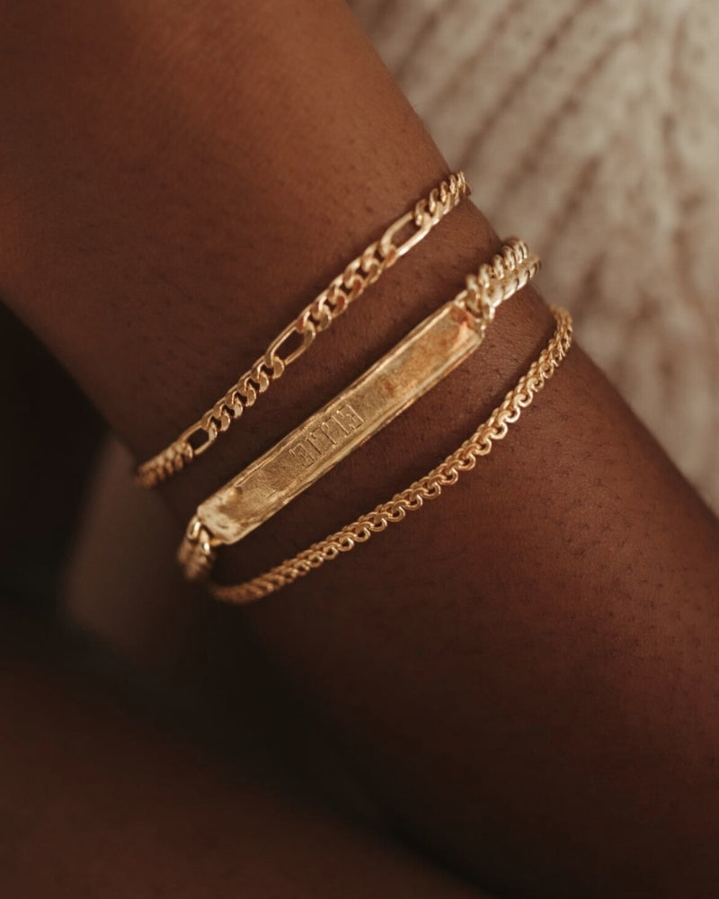 A close up view of the Signature Bracelet in Gold Vermeil. It is worn in between the Figaro Bracelet and Lace Chain Bracelet by Bluebird Jewellery.