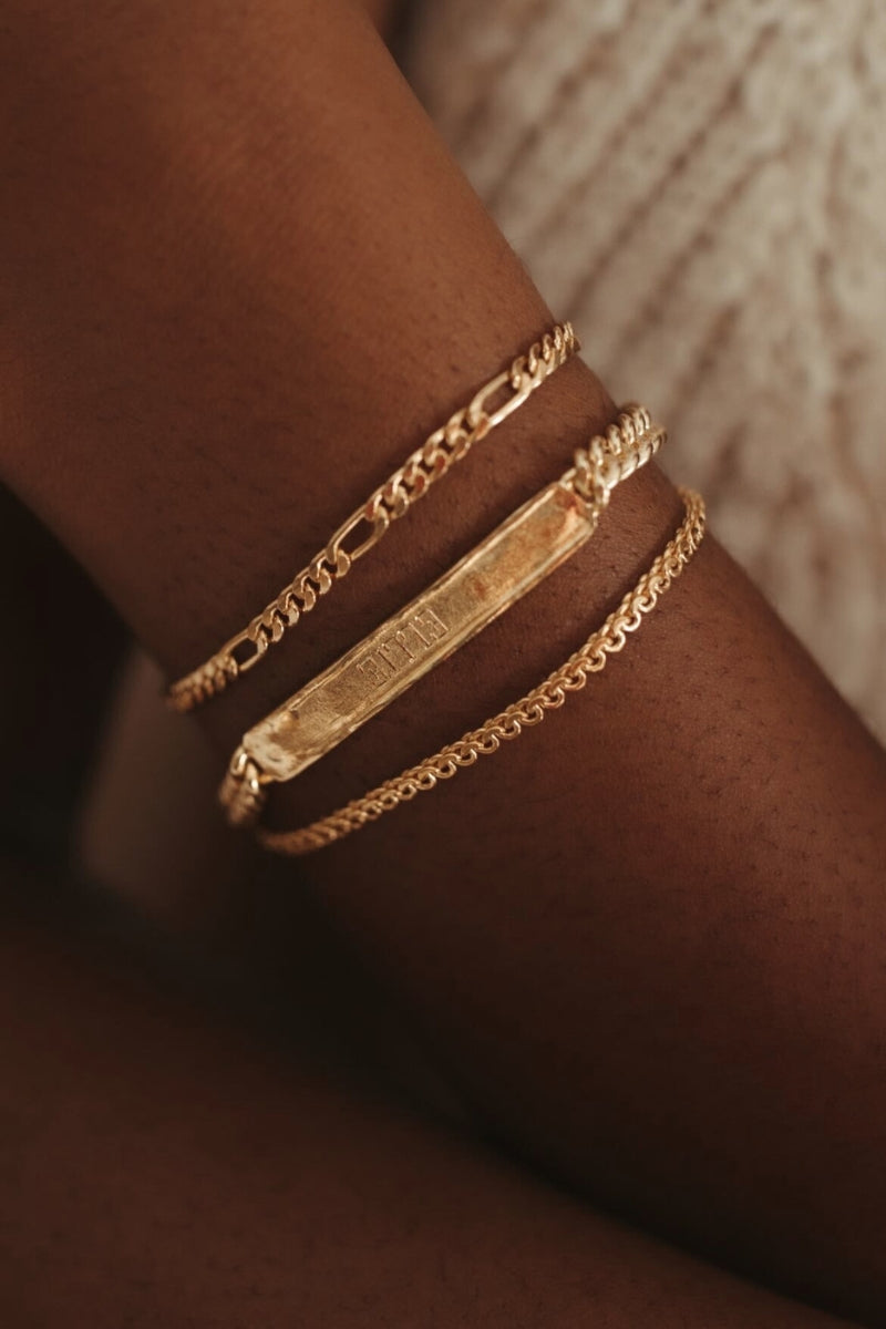A close up view of the Signature Bracelet in Gold Vermeil. It is worn in between the Figaro Bracelet and Lace Chain Bracelet by Bluebird Jewellery.