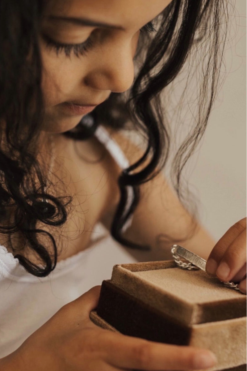 Young girl opening jewellery box with engraved signature silver bracelet inside by Bluebird Jewellery.