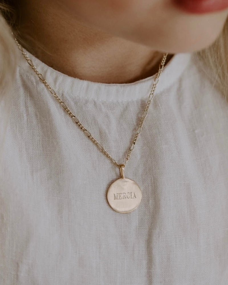 A young girl is wearing the child length Signature Necklace with her name engraved on the front of the personalised pendant.