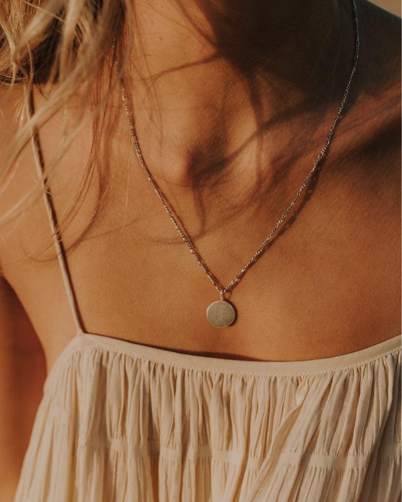 Silver necklace with engraved round pendant and figaro chain.