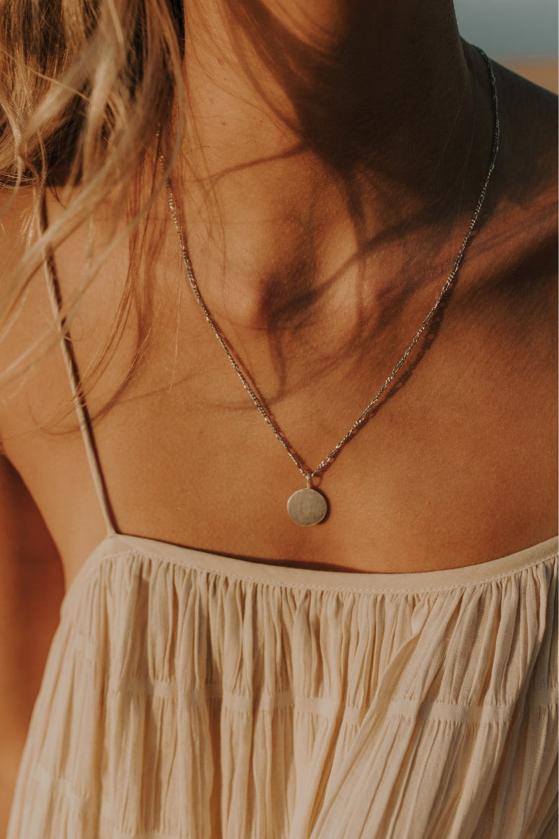 Silver necklace with engraved round pendant and figaro chain.