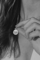 Engraved silver round pendant necklace held by figaro chain.