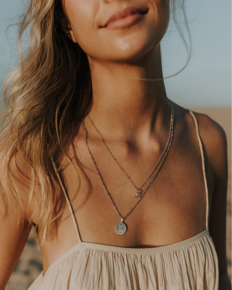 Layered silver engraved pendant necklaces with fine chains.