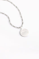 Engraved silver round pendant necklace with figaro-style chain.
