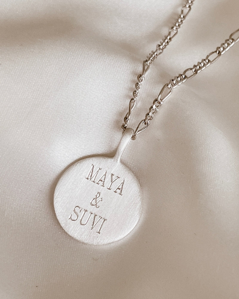 Silver round pendant necklace engraved with two names.