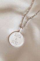 Silver round pendant necklace engraved with two names.