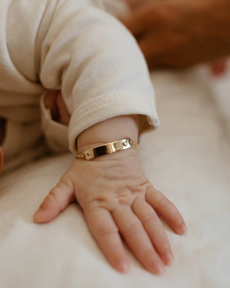 Baby wearing solid gold Darling Bracelet with engraved nameplate and heart detail, a forever keepsake piece by Bluebird Jewellery