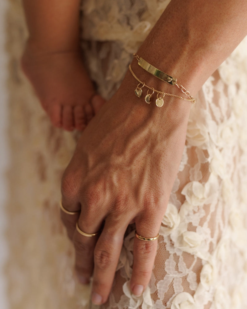 Mum wearing stacked solid gold Darling Bracelet with engraved pendants by Bluebird Jewellery