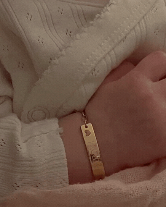 Baby wearing an engraved 9ct solid gold Pink Darling Bracelet with a pink heart charm by Bluebird Jewellery, crafted as a timeless keepsake.