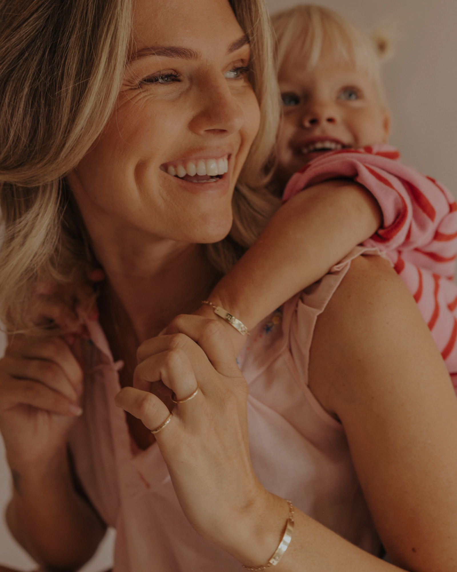 Mum and daughter wearing matching 9ct solid gold Pink Darling Bracelets with pink heart detail. Bluebird Jewellery.