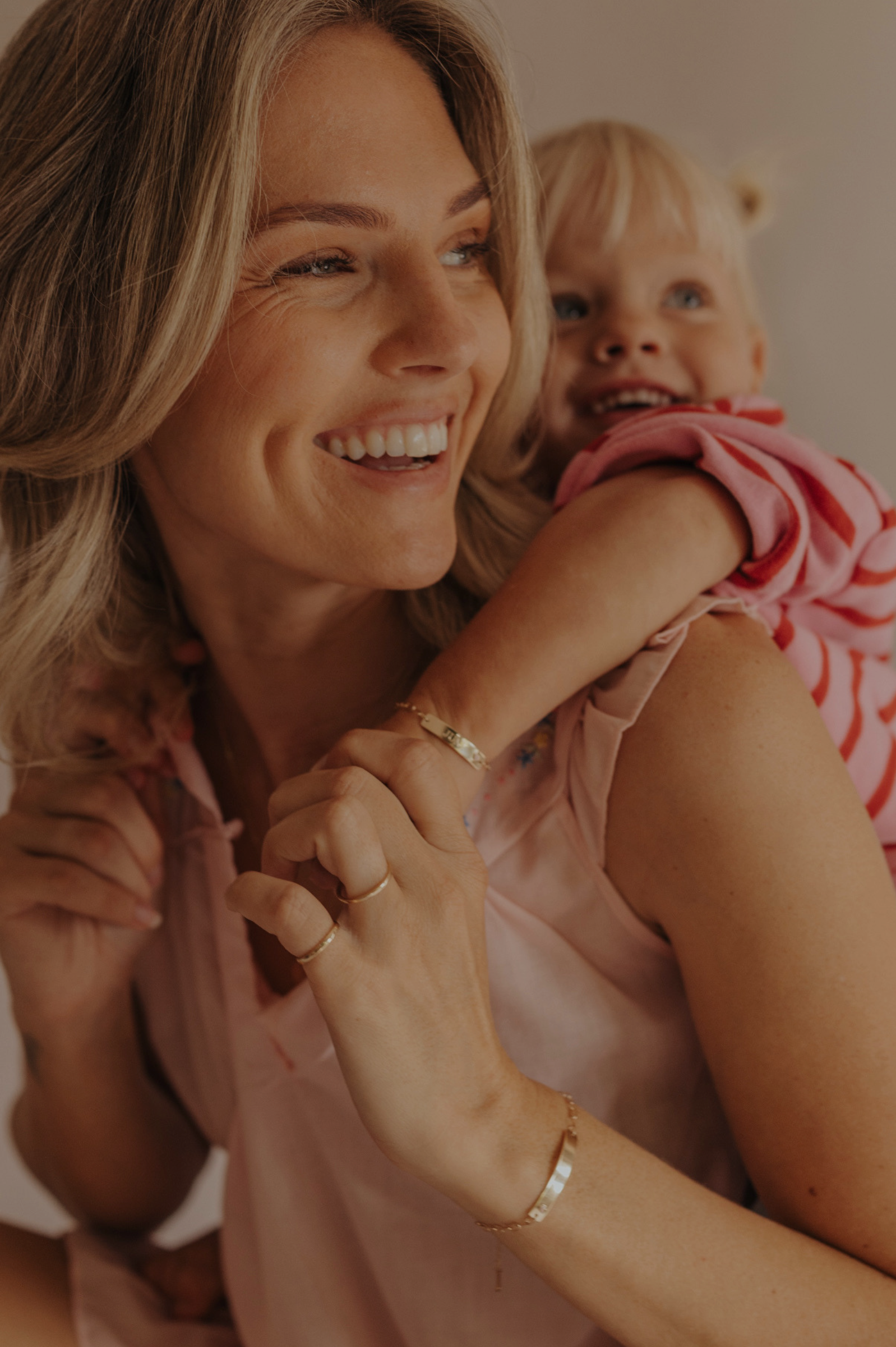 Mum and daughter wearing matching 9ct solid gold Pink Darling Bracelets with pink heart detail. Bluebird Jewellery.