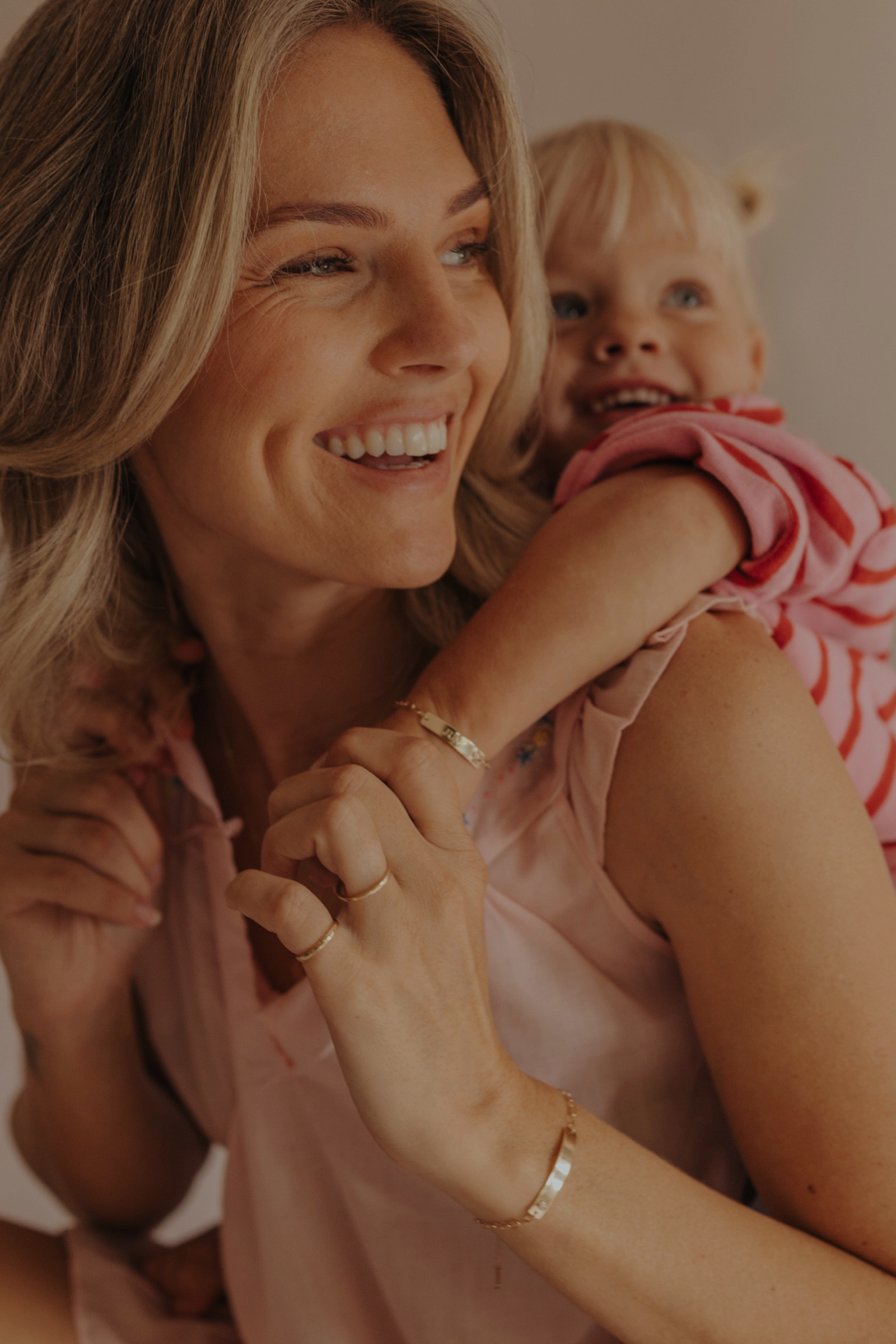 Mum and daughter wearing matching 9ct solid gold Pink Darling Bracelets with pink heart detail. Bluebird Jewellery.