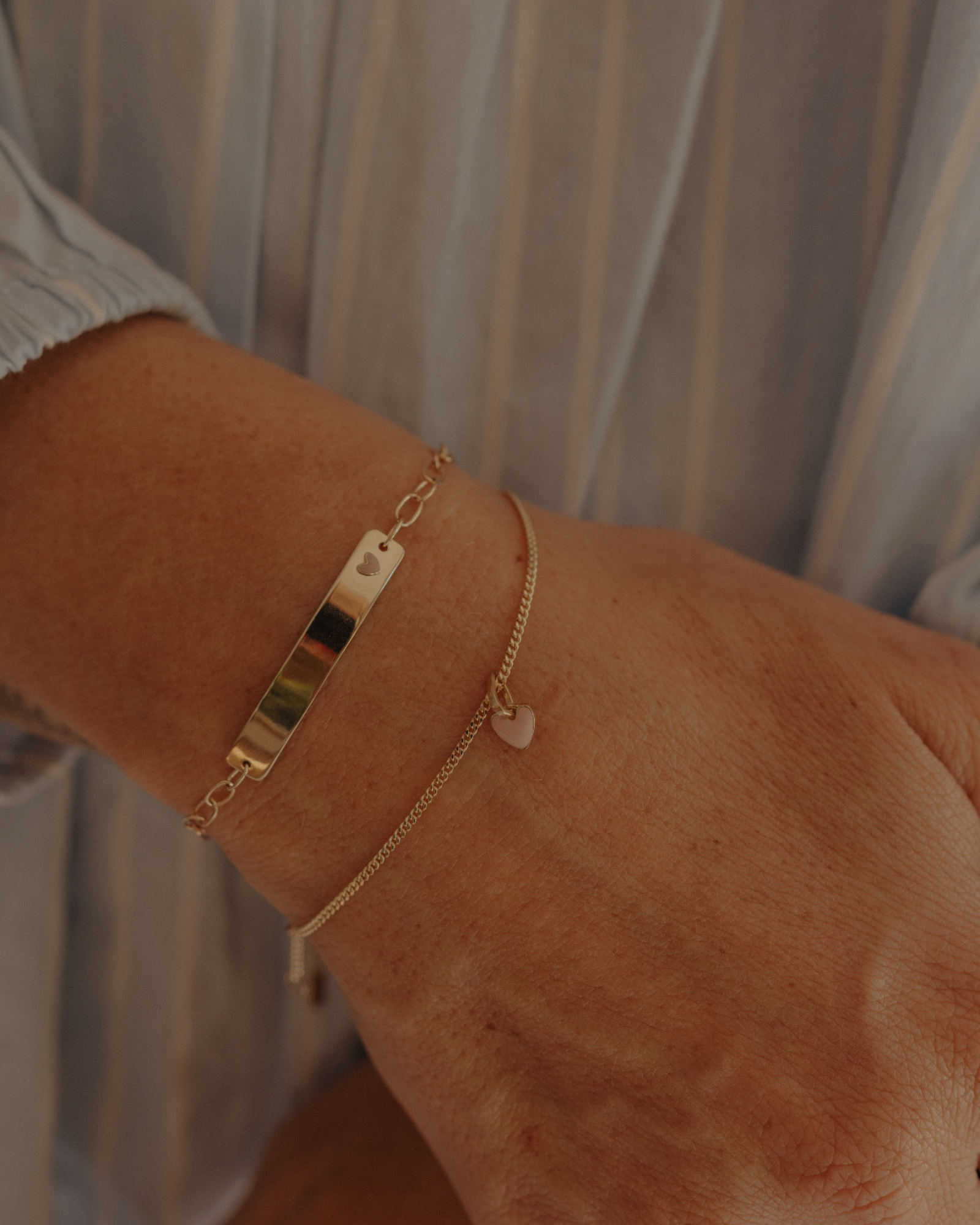 Mum’s wrist with stacked solid gold Pink Darling and heart chain bracelets, elegant keepsake jewellery