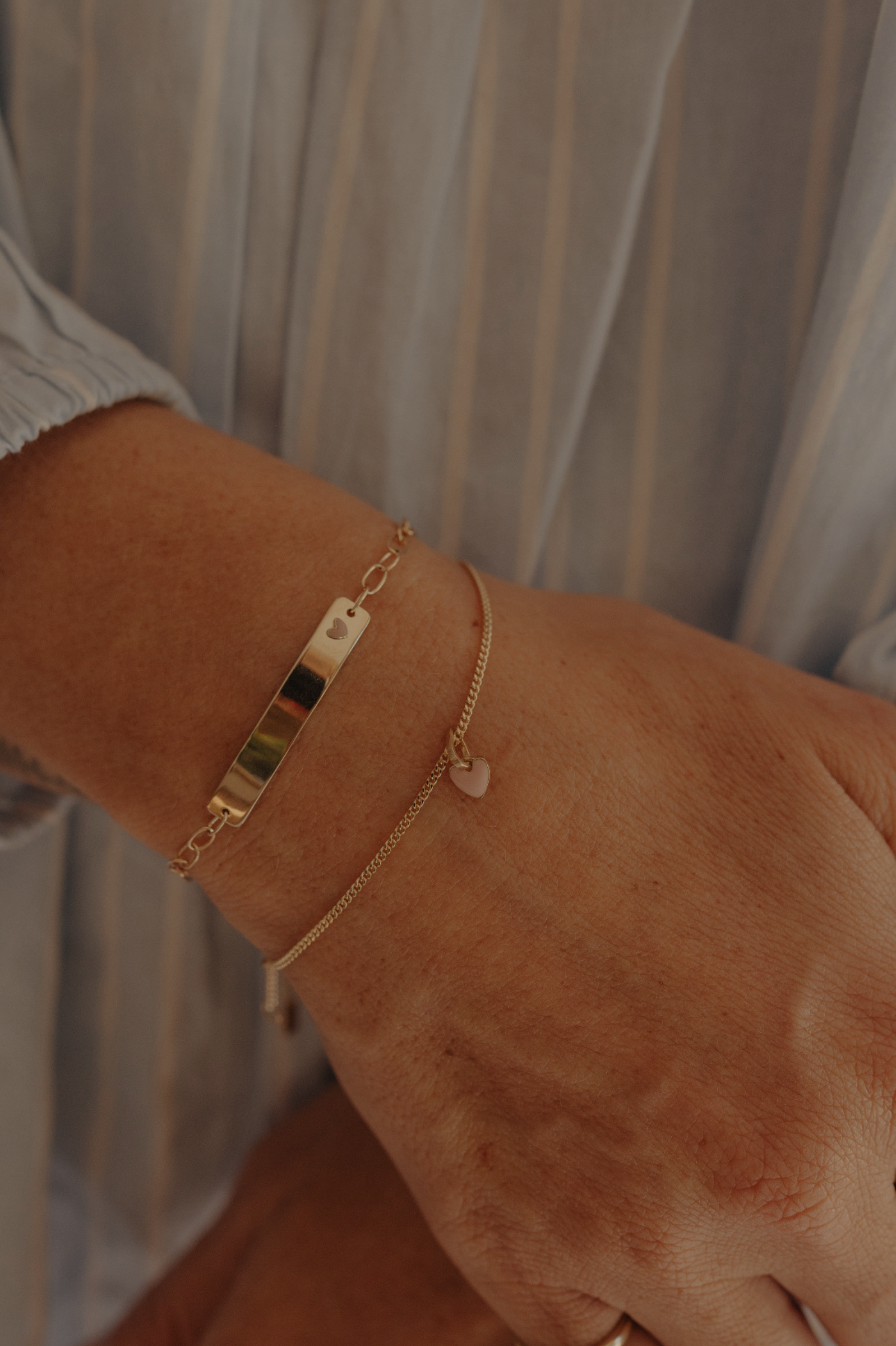 Mum’s wrist with stacked solid gold Pink Darling and heart chain bracelets, elegant keepsake jewellery