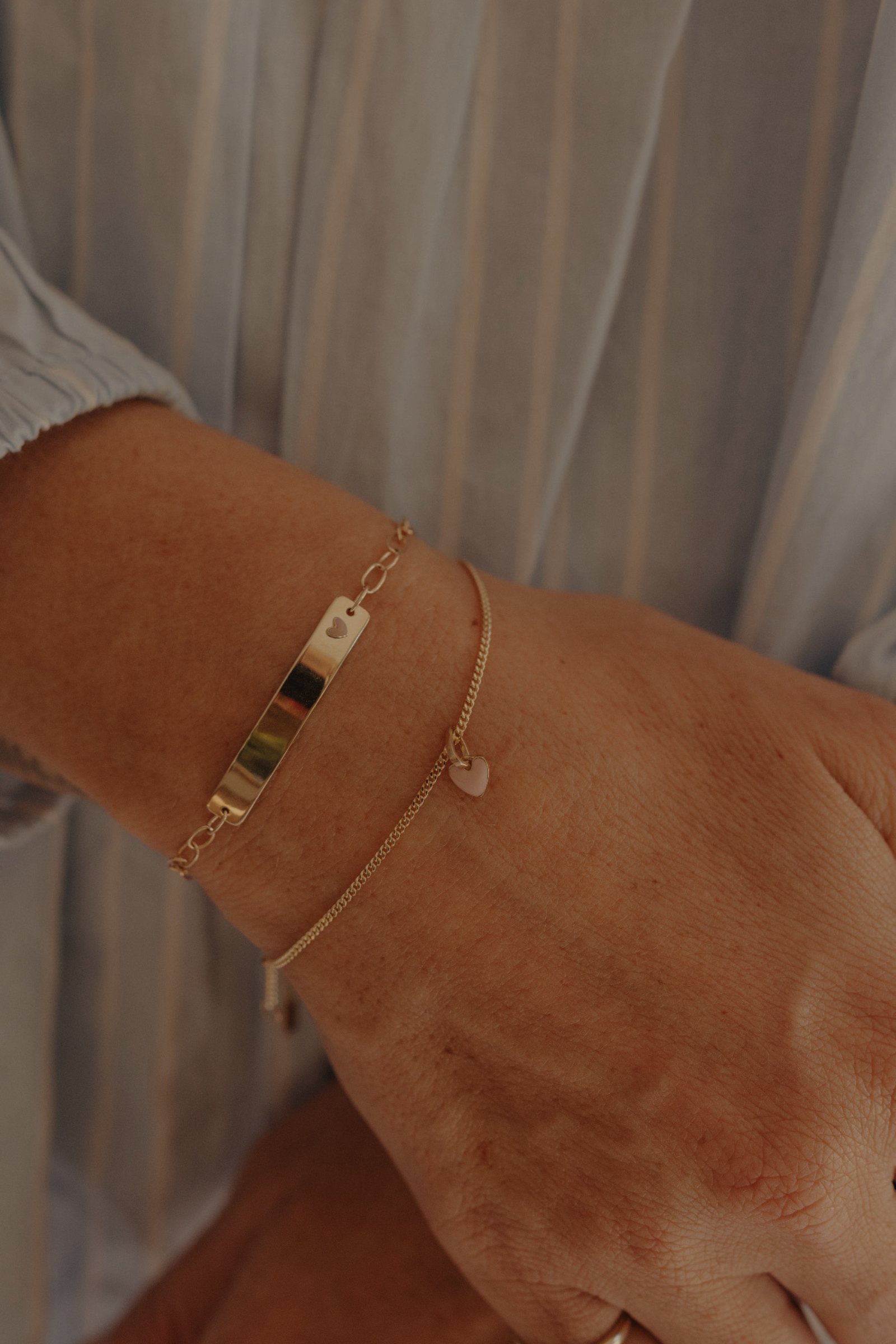 Mum’s wrist with stacked solid gold Pink Darling and heart chain bracelets, elegant keepsake jewellery