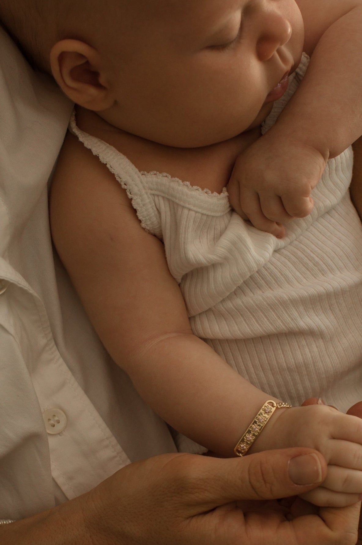 A baby girl is wearing the Daisy Bracelet in Gold Vermeil by Bluebird Jewellery.