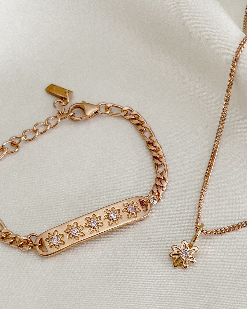 A close-up of the Daisy Bracelet and Daisy Necklace by Bluebird Jewellery, featuring hand-drawn daisy details and pink cubic zirconia accents for a touch of sparkle.