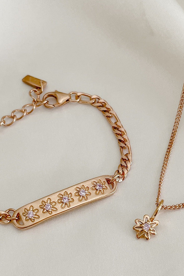 A close-up of the Daisy Bracelet and Daisy Necklace by Bluebird Jewellery, featuring hand-drawn daisy details and pink cubic zirconia accents for a touch of sparkle.