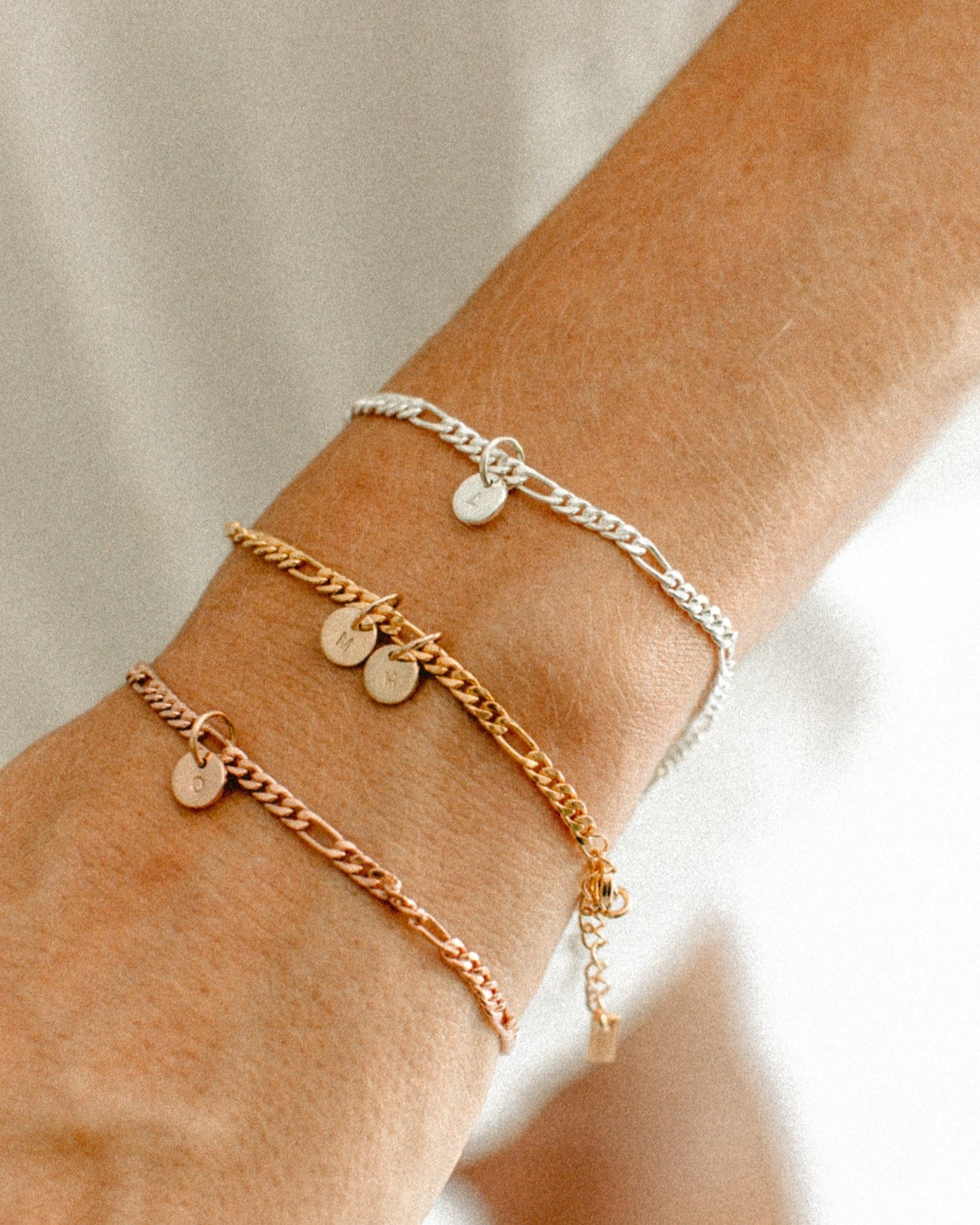 Three Figaro bracelets are on a woman'd wrist to show rose gold, gold and sterling silver colour variations by Bluebird Jewellery