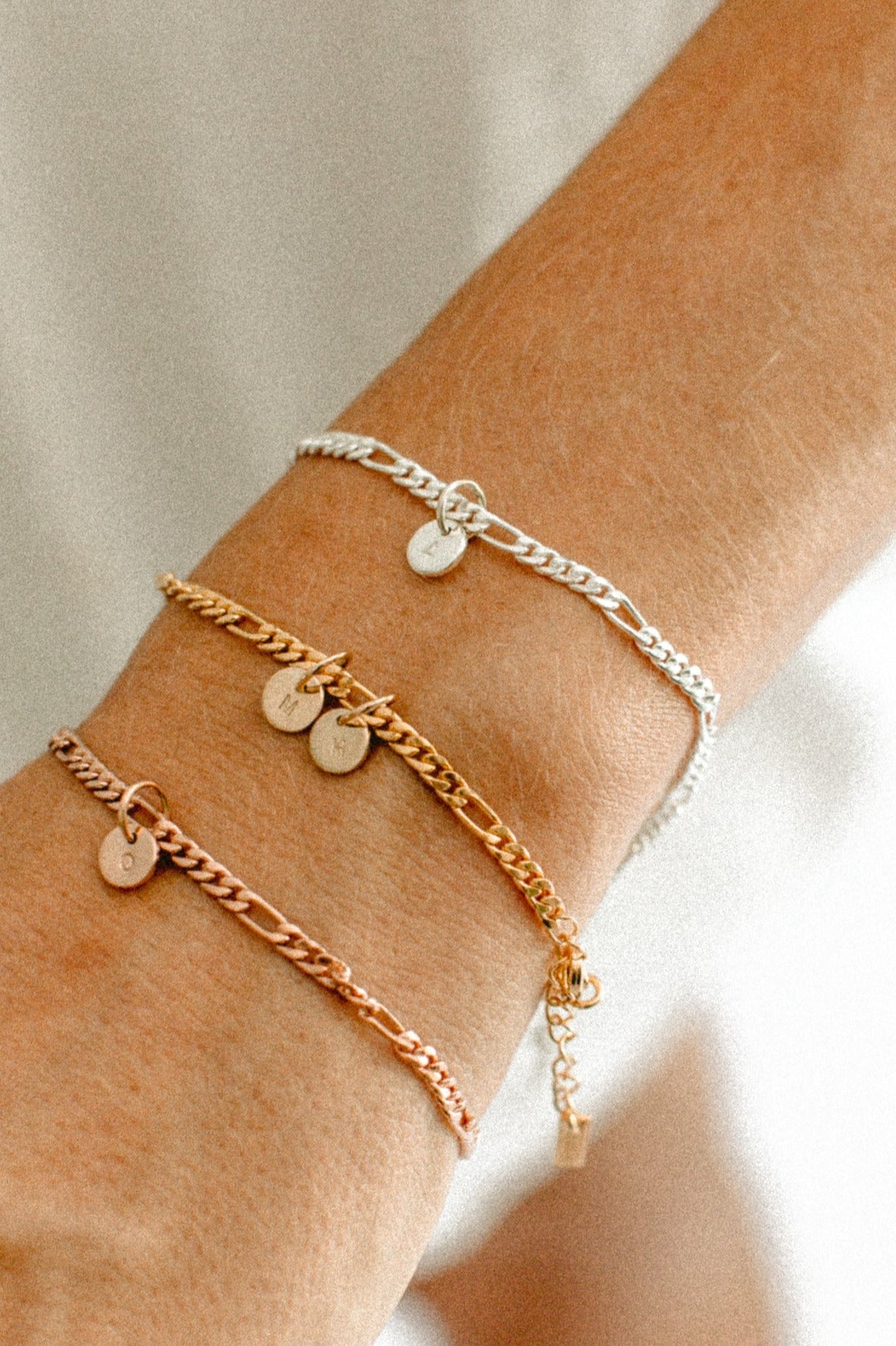 Three Figaro bracelets are on a woman'd wrist to show rose gold, gold and sterling silver colour variations by Bluebird Jewellery