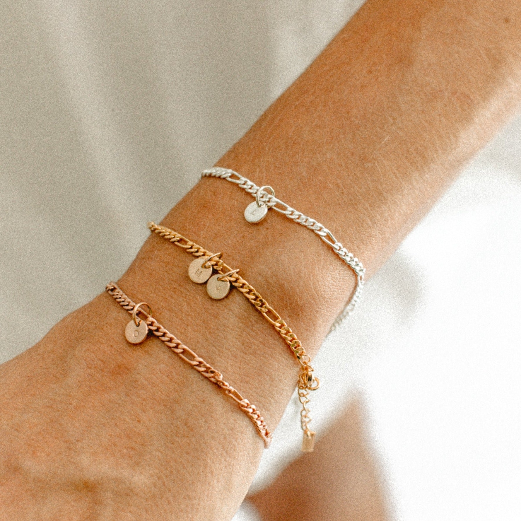 Three Figaro bracelets are on a woman'd wrist to show rose gold, gold and sterling silver colour variations by Bluebird Jewellery