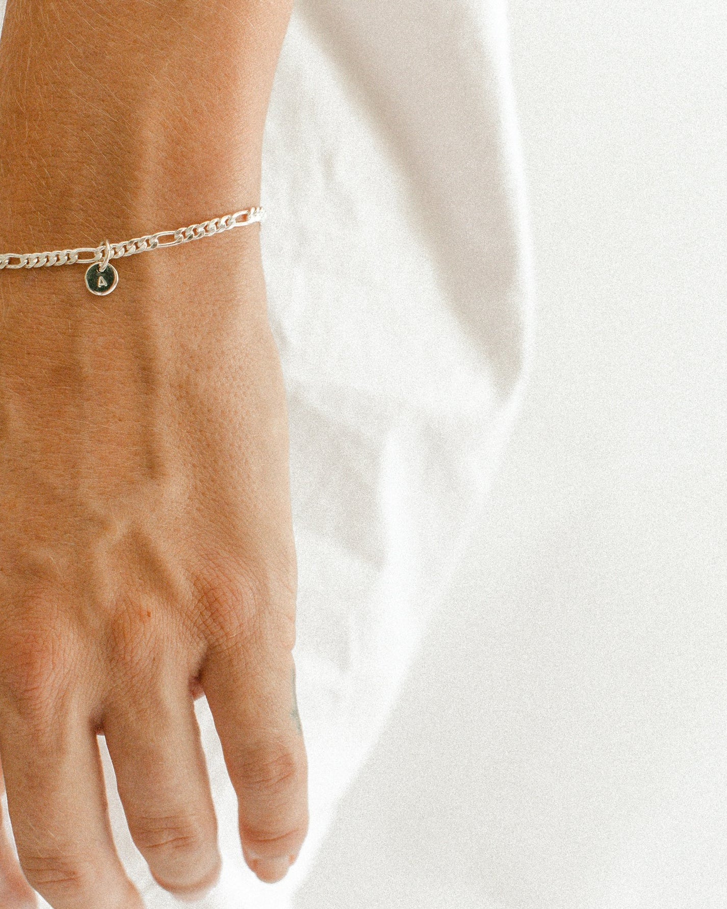 A Figaro Bracelet in adult length worn with one 6mm initial pendant by Bluebird Jewellery